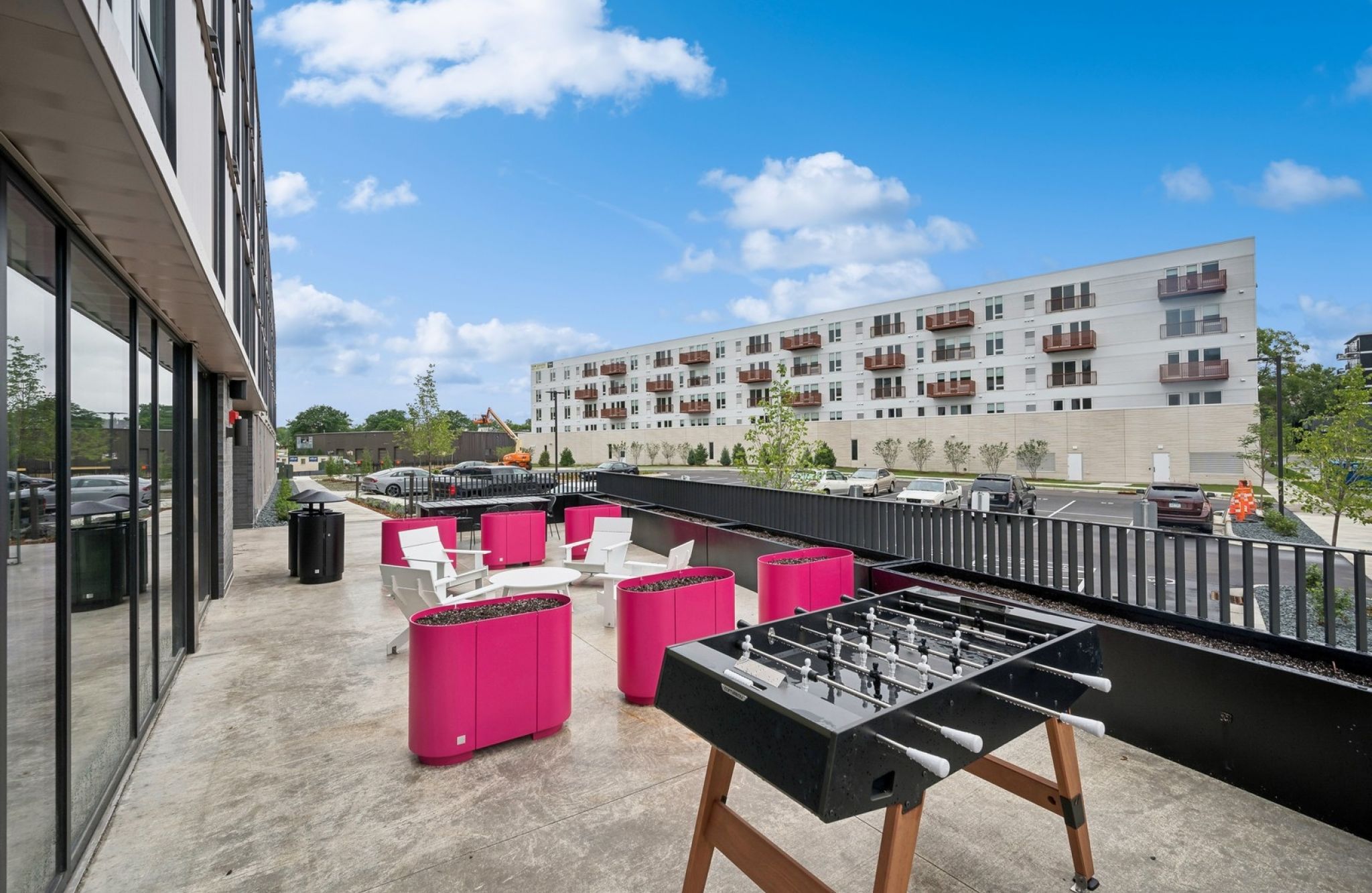 Outdoor patio at Harbourline featuring bright pink seating, a foosball table, and ample space for relaxation.